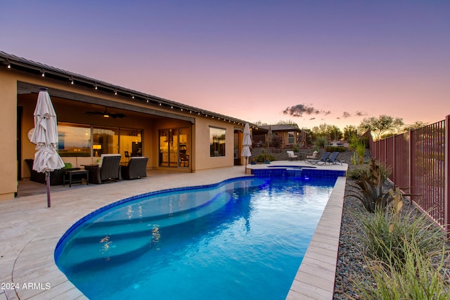 pool at dusk with a patio area, ceiling fan, and an outdoor hangout area