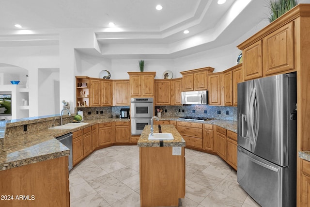 kitchen featuring appliances with stainless steel finishes, sink, a center island with sink, and a tray ceiling