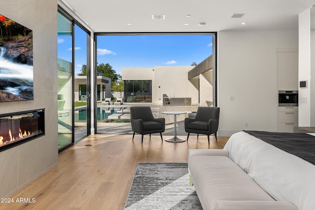 bedroom with a wall of windows, access to exterior, and light hardwood / wood-style flooring