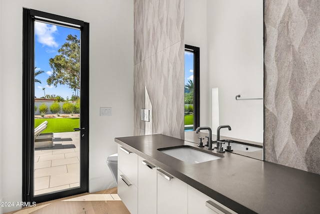 kitchen featuring plenty of natural light, white cabinetry, sink, and light hardwood / wood-style flooring