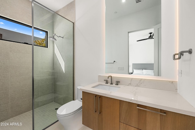 bathroom with a tile shower, vanity, ceiling fan, and toilet