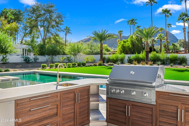 view of swimming pool with a patio area, sink, a mountain view, and a grill