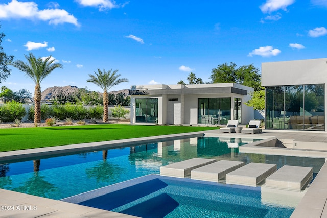 view of pool with a patio, a lawn, and a mountain view