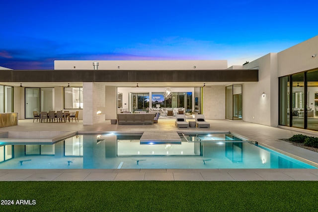 back house at dusk featuring a patio area and an outdoor living space