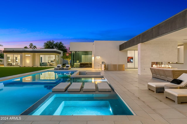 pool at dusk featuring an in ground hot tub and a patio area