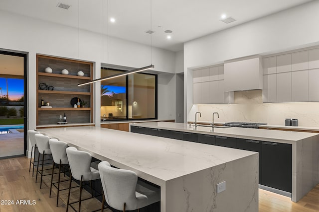 kitchen featuring a center island with sink, sink, and light hardwood / wood-style flooring