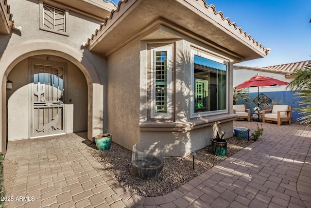 exterior space with a patio area, a tiled roof, and stucco siding