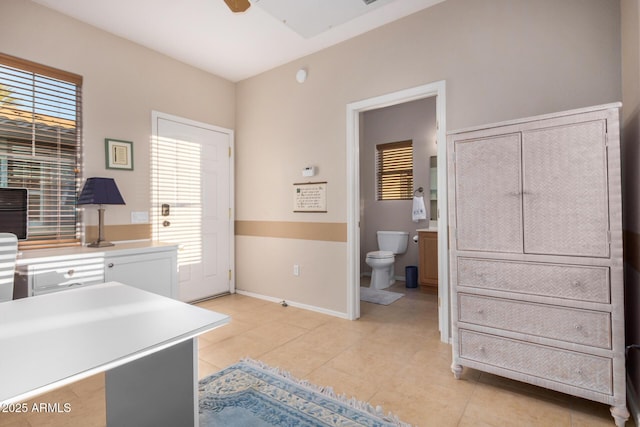 office space with light tile patterned floors, baseboards, a ceiling fan, and a wealth of natural light