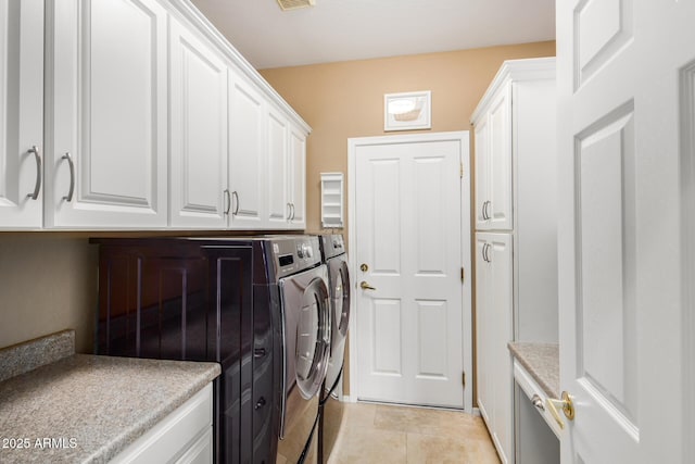 clothes washing area featuring visible vents, cabinet space, washer and clothes dryer, and light tile patterned floors