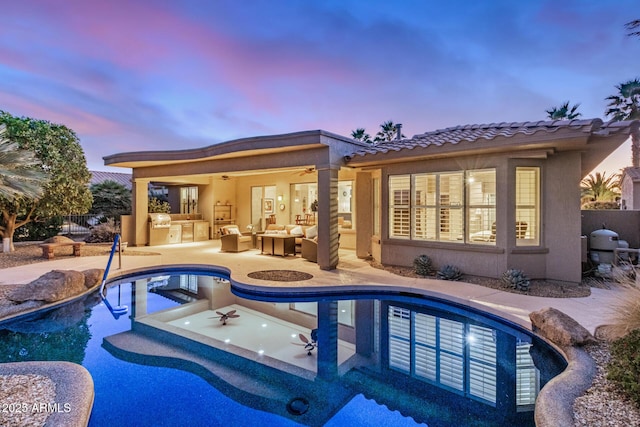 pool with a patio, outdoor lounge area, fence, a ceiling fan, and exterior kitchen