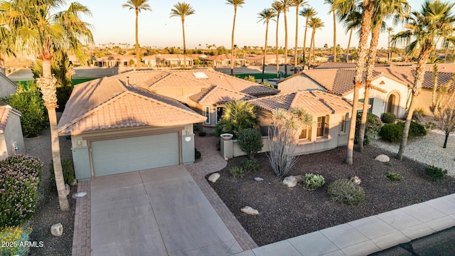 mediterranean / spanish-style house with driveway, a tile roof, a residential view, an attached garage, and stucco siding