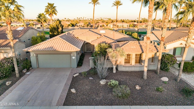 mediterranean / spanish-style house with a garage, a tile roof, concrete driveway, a residential view, and stucco siding