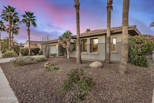 view of front of home featuring an attached garage, a tile roof, and stucco siding