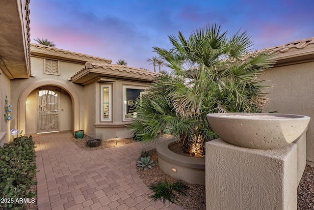 exterior space featuring a patio area, a tile roof, and stucco siding