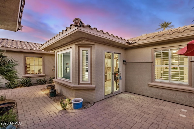 exterior space featuring a patio, a tiled roof, and stucco siding