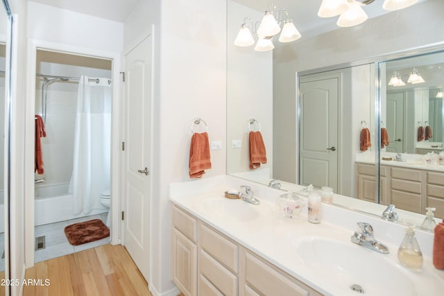 full bath featuring double vanity, wood finished floors, a sink, and toilet