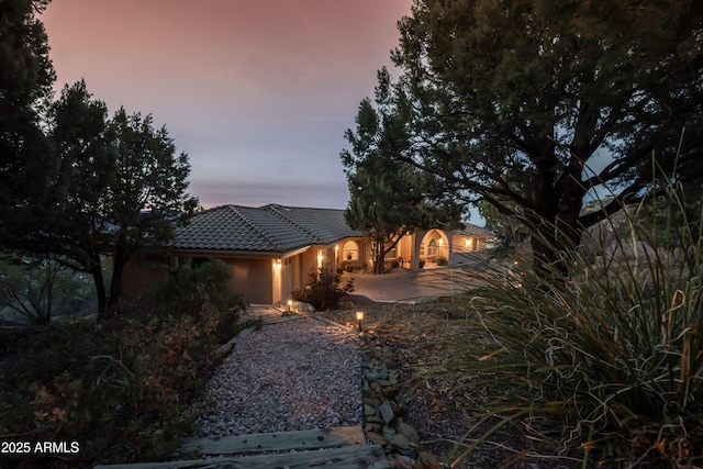 view of front of property featuring a patio, a tile roof, and stucco siding