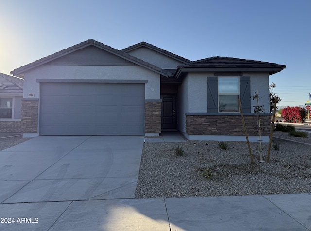 ranch-style home with stucco siding, concrete driveway, a garage, stone siding, and a tiled roof