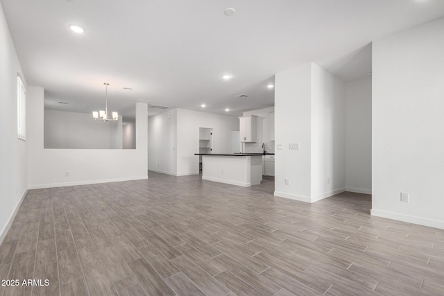 unfurnished living room with a chandelier, recessed lighting, and light wood finished floors