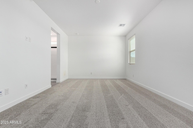 carpeted spare room with visible vents and baseboards