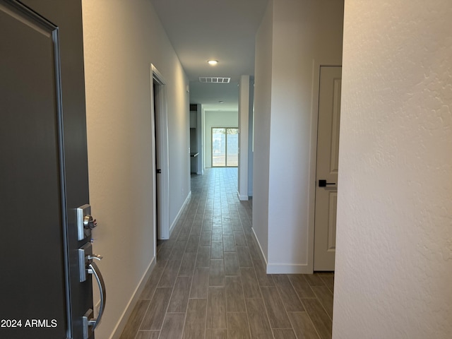 hallway featuring wood finish floors, visible vents, and baseboards