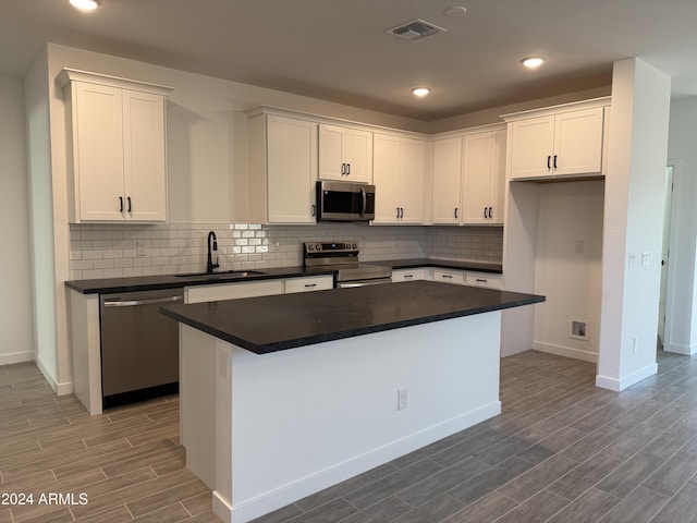 kitchen with white cabinetry, a center island, sink, wood-type flooring, and appliances with stainless steel finishes