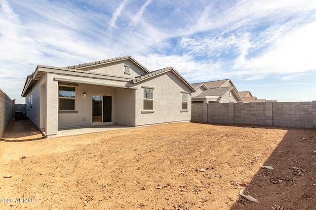 rear view of house featuring a patio area, a fenced backyard, central AC, and stucco siding