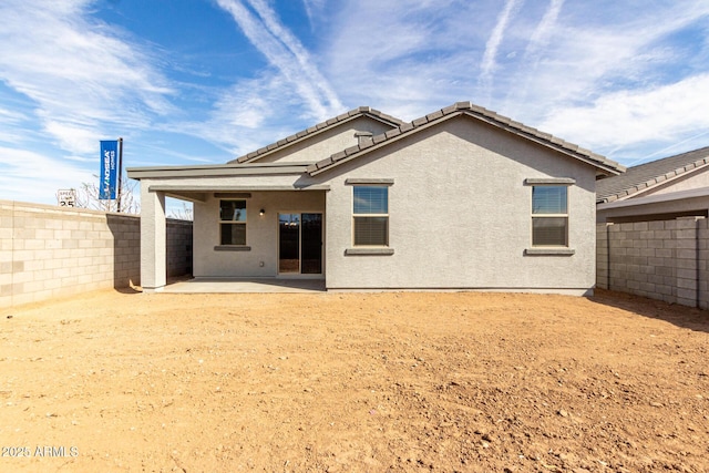 rear view of property featuring a tile roof, a fenced backyard, a patio, and stucco siding