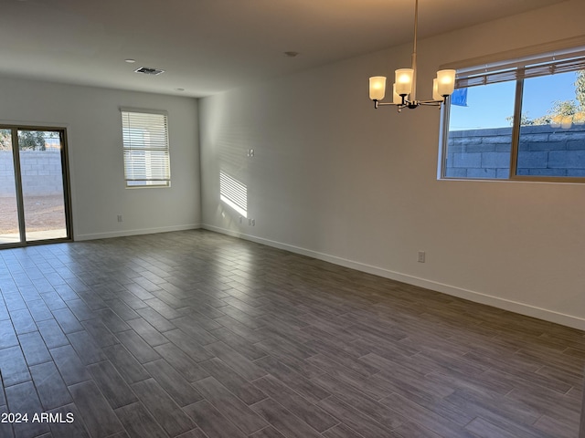 unfurnished room with dark hardwood / wood-style flooring, plenty of natural light, and an inviting chandelier