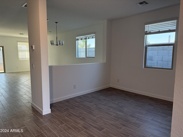 spare room with baseboards, an inviting chandelier, visible vents, and wood tiled floor