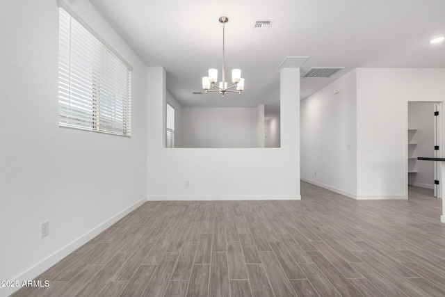 spare room with visible vents, a notable chandelier, and wood finished floors