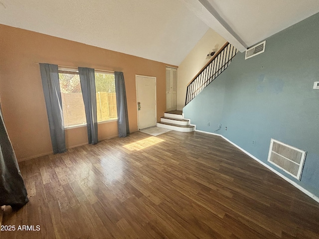 unfurnished living room featuring hardwood / wood-style floors and vaulted ceiling with beams