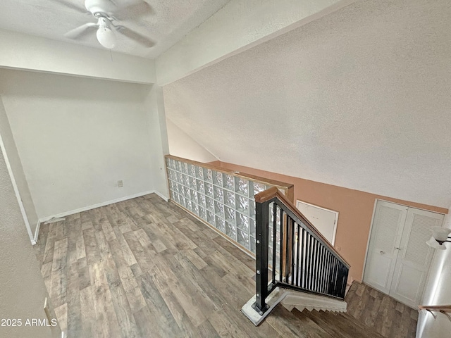 stairs featuring lofted ceiling, ceiling fan, a mail area, a textured ceiling, and wood-type flooring