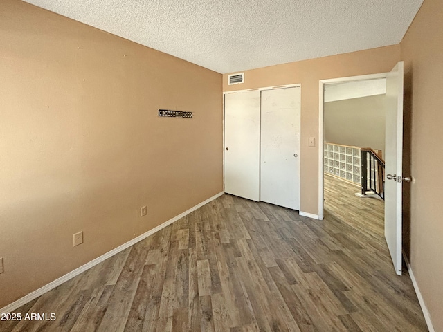 unfurnished bedroom with a closet, hardwood / wood-style floors, and a textured ceiling