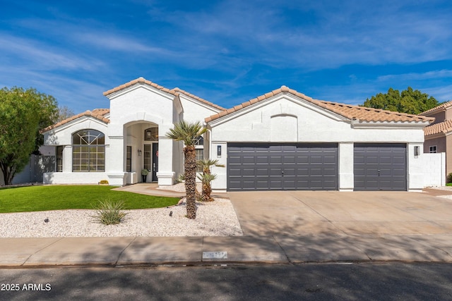 mediterranean / spanish-style house with a garage, concrete driveway, a tiled roof, a front lawn, and stucco siding