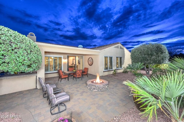 patio terrace at dusk featuring a fire pit