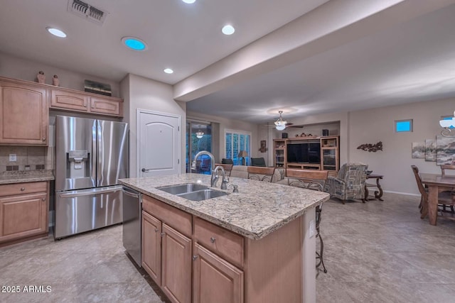 kitchen featuring sink, ceiling fan, stainless steel appliances, a kitchen breakfast bar, and a center island with sink