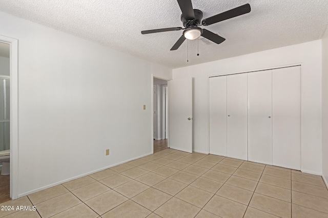 unfurnished bedroom featuring a textured ceiling, light tile patterned floors, ceiling fan, and a closet