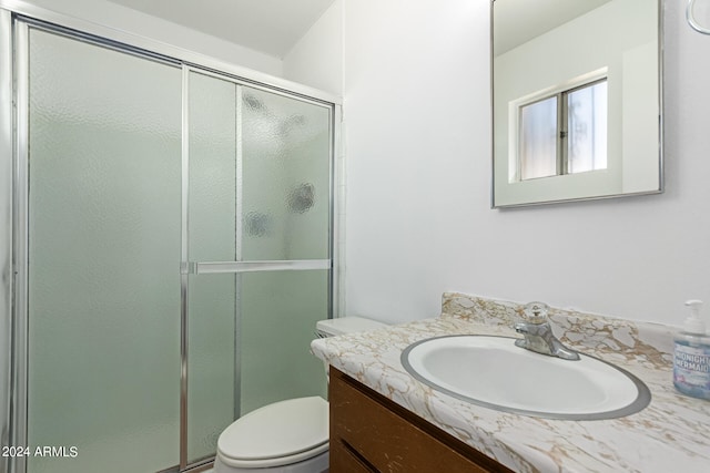 bathroom with toilet, a shower with door, and vanity