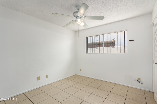 tiled spare room with a textured ceiling and ceiling fan