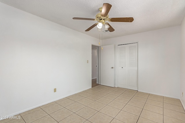 unfurnished bedroom with a textured ceiling, light tile patterned floors, ceiling fan, and a closet