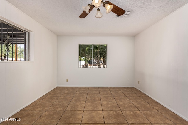 unfurnished room featuring a textured ceiling, dark tile patterned floors, and ceiling fan