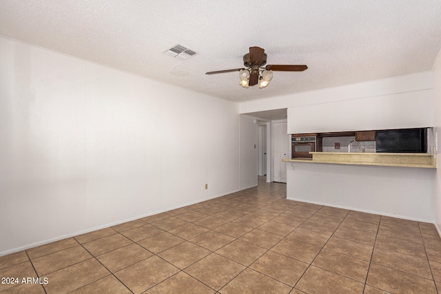 unfurnished living room with tile patterned flooring, ceiling fan, and a textured ceiling