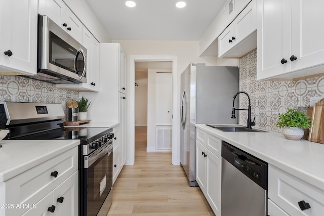 6001 N 10th Way, Phoenix, AZ 85014 - kitchen with stainless steel appliances, a sink, recessed lighting, white cabinets, and light wood-style floors