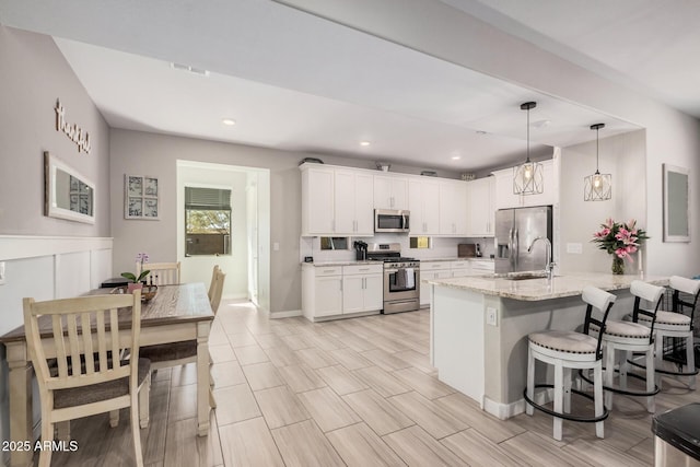 16573 W Alameda Rd, Surprise, AZ 85387 - kitchen with a sink, appliances with stainless steel finishes, a breakfast bar area, and white cabinetry