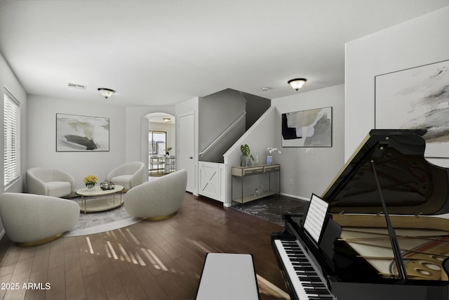 living room featuring arched walkways, dark wood finished floors, visible vents, and plenty of natural light