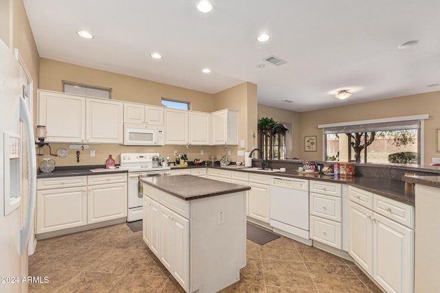 kitchen featuring white appliances, sink, light tile patterned floors, white cabinetry, and kitchen peninsula