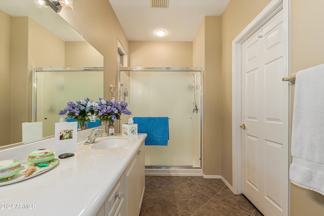 bathroom with a shower with door, vanity, and tile patterned flooring