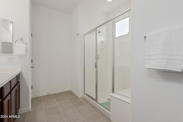 bathroom with walk in shower, vanity, and tile patterned floors