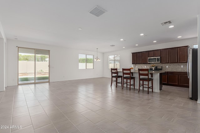 kitchen featuring an island with sink, a kitchen bar, appliances with stainless steel finishes, and light tile patterned floors